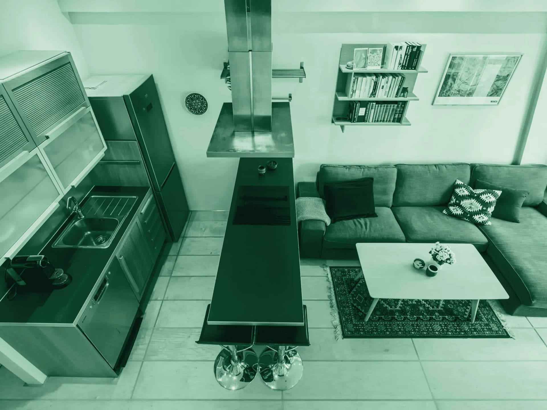 Looking down from the ceiling into a bright room with a long counter, stools and a sofa